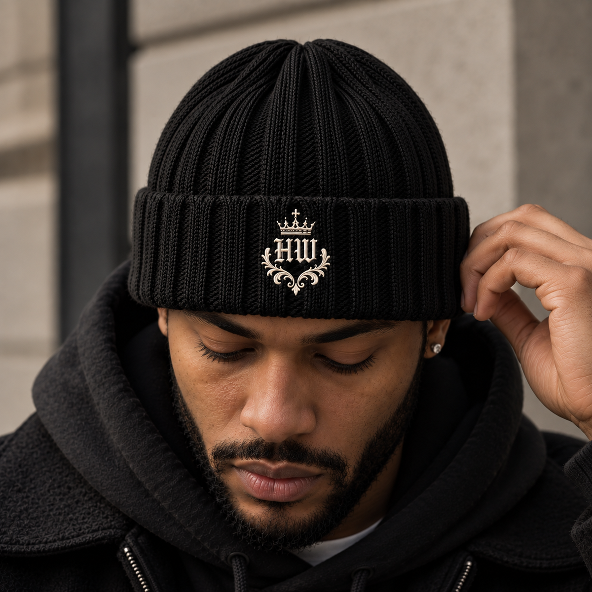 Model wearing HLY WTR Heritage Crest ribbed beanie in black with off-white embroidered HW crest.