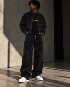 Model wearing the HLY WTR Heritage Monogram black denim jacket and wide-leg jeans with tonal HW pattern details