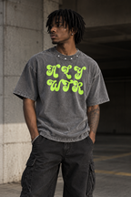 Model wearing HLY WTR washed grey oversized T-shirt with neon green logo and studded collar